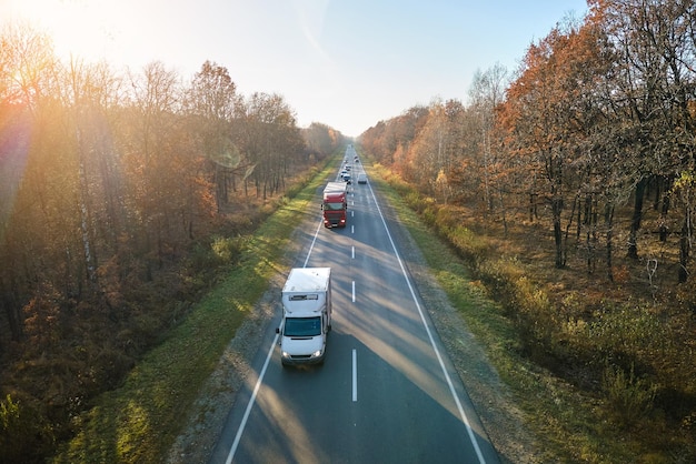 Aerial view of cargo trucks driving on highway hauling goods. Delivery transportation and logistics concept