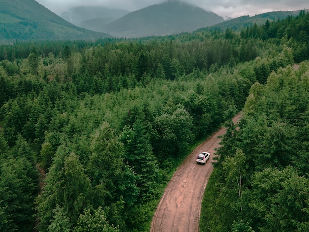 Aerial view of carpathian mountains overcast weather suv car on trail road copy space