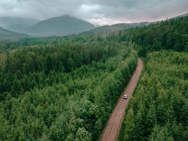 Aerial view of carpathian mountains overcast weather suv car on trail road copy space