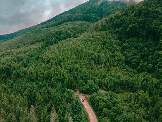 Aerial view of carpathian mountains overcast weather suv car on trail road