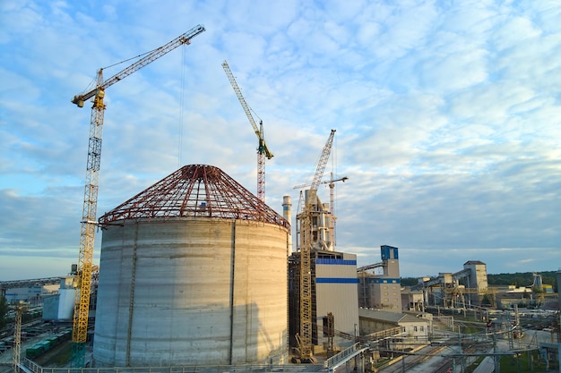 Aerial view of cement factory under construction with high concrete plant structure and tower cranes at industrial production area Manufacture and global industry concept