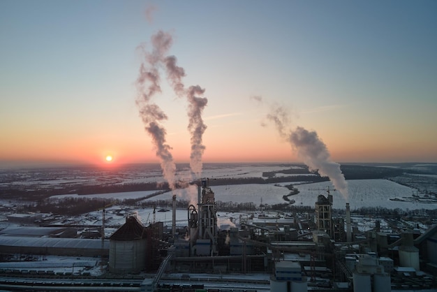 Aerial view of cement factory with high concrete plant structure and tower crane at industrial production area in evening Manufacture and global industry concept