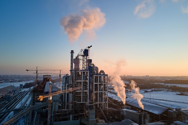 Aerial view of cement factory with high concrete plant structure and tower cranes at industrial production area Greenhouse gas smoke polluting atmosphere Manufacture and global industry concept