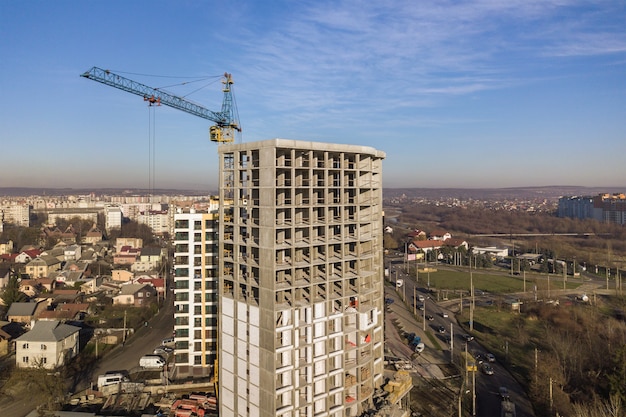 Aerial view of concrete frame of tall apartment building under construction in a city.