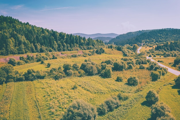 Aerial view of the countryside country road and cultivated fields on the hills on a sunny spring day