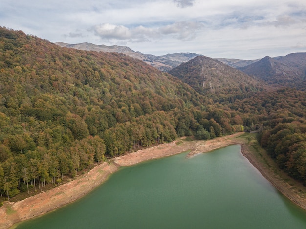 Aerial view of a dam at sunset on a cloudy day in the middle of a mountainous forest. Dam on a mountain river