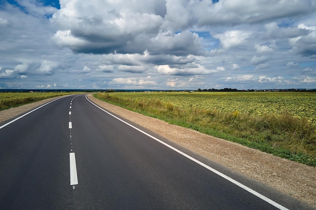 Aerial view of empty intercity road between green agricultural fields Top view from drone of highway roadway