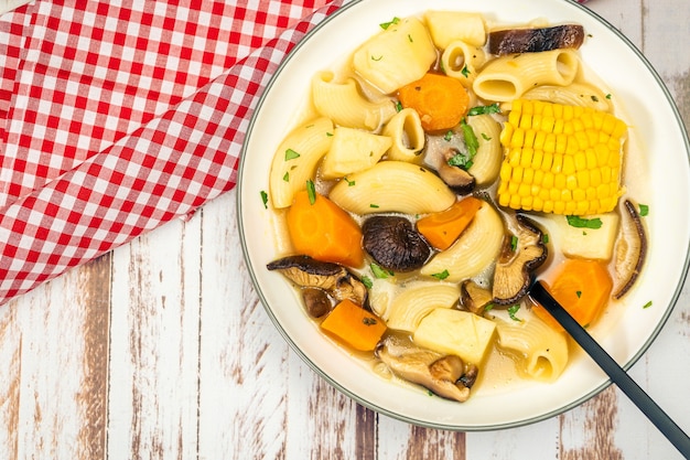 Aerial view of an exquisite homemade chicken, vegetable and mushroom soup with noodles and corn. Natural and healthy food concept. Copy space.