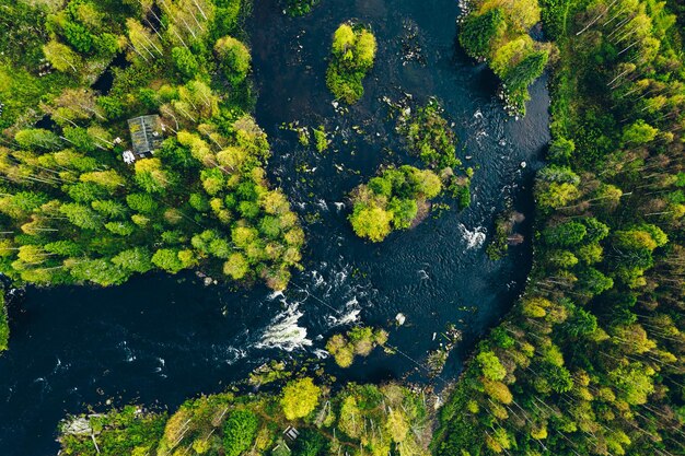 Aerial view of fast blue river in beautiful green spring forest in Finland