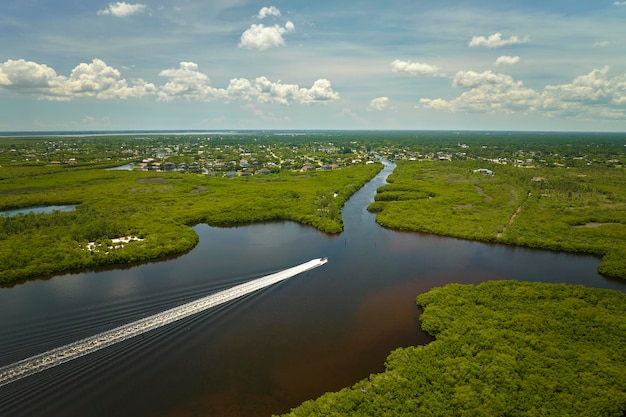 Aerial view of Florida wetlands with small motorboat swimming between green vegetation in water inlets Recreation in nature concept