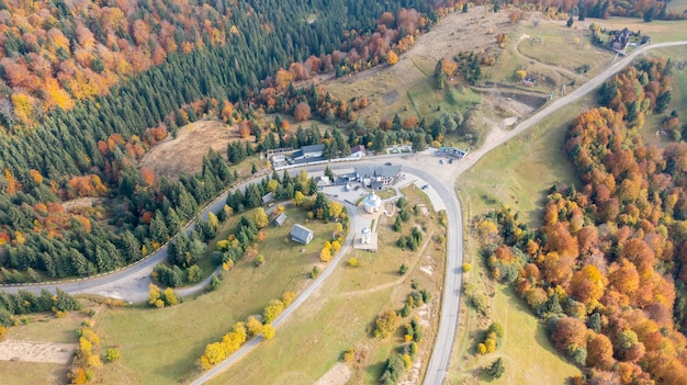 Aerial view of forest road in beautiful autumn at sunset. Curved road in the mountains with truck traffic