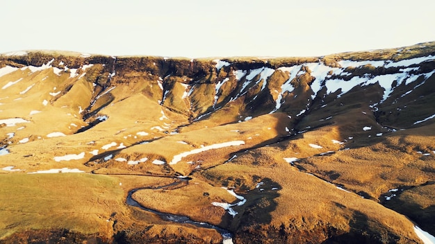 Aerial view of foss a sidu waterfall creating fantastic frozen landscape, icelandic scenery. Beautiful scandinavian cascade running down off of hills, scenic route. Slow motion.