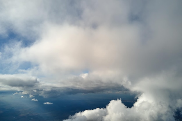 Aerial view from airplane window at high altitude of earth covered with puffy cumulus clouds forming before rainstorm