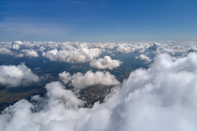 Aerial view from airplane window at high altitude of earth covered with white puffy cumulus clouds