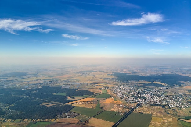 Aerial view from airplane window at high altitude of earth covered with white thin layer of misty haze and distant clouds at sunset