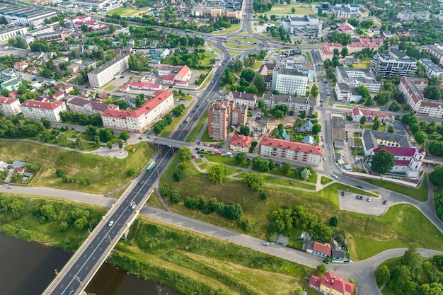 Aerial view from great height on red roofs of old city with heavy traffic on bridge with wide multilane road across wide river