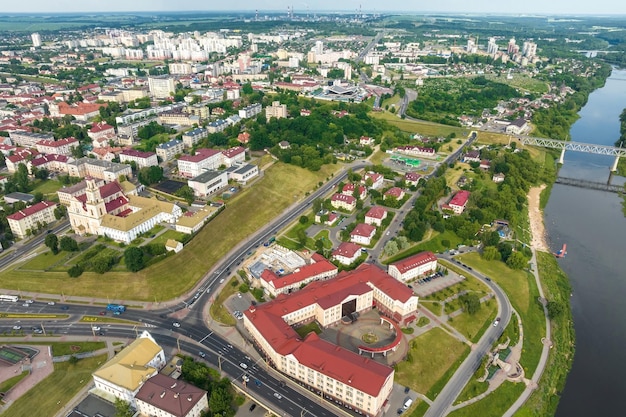 Aerial view from great height on red roofs of old city with heavy traffic on bridge with wide multilane road across wide river