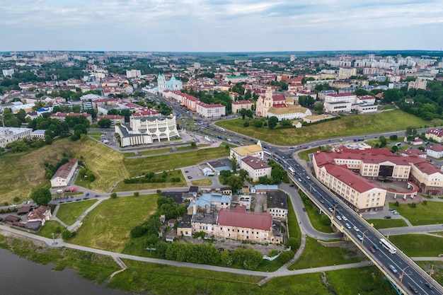 Aerial view from great height on red roofs of old city with heavy traffic on bridge with wide multilane road across wide river