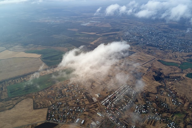 Aerial view from high altitude of distant city covered with puffy cumulus clouds forming before rainstorm Airplane point of view of cloudy landscape