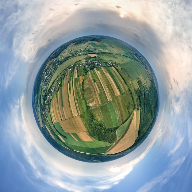 Aerial view from high altitude of little planet earth with green and yellow cultivated agricultural fields with growing crops on bright summer day