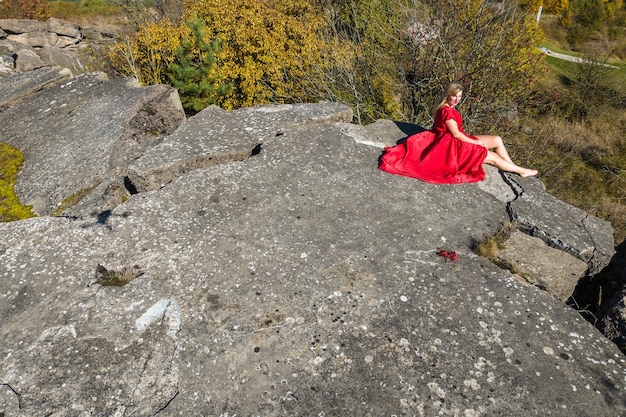 Aerial view on girl in red dress on rock or concrete ruined structure