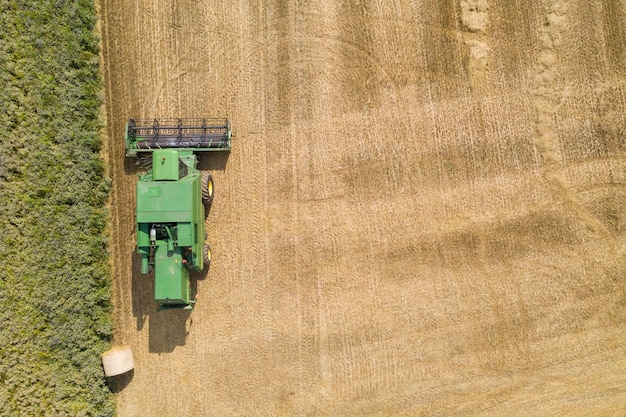 Aerial view over a green combine harvester in a farm field