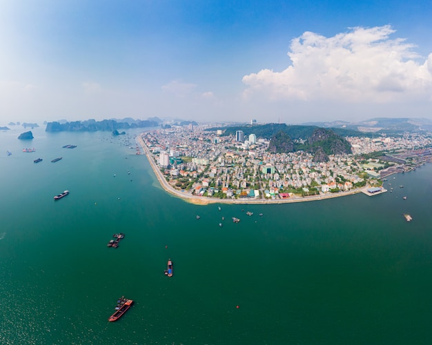 Aerial view of Ha Long Bay and Halong City skyline, unique limestone rock islands and karst formation peaks in the sea, famous tourism destination in Vietnam. Scenic blue sky and mist.