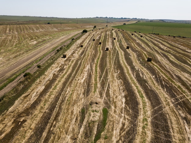 Aerial view to harvested field with straw bales in summer