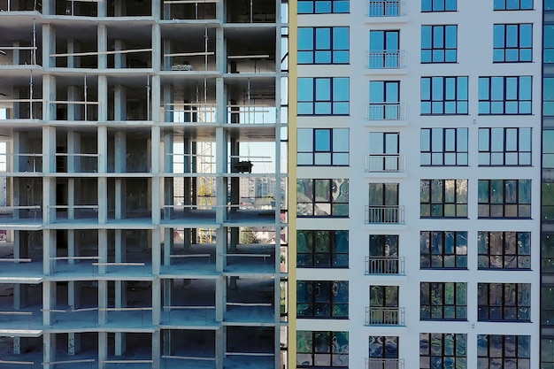 Aerial view of high residential apartment building under construction. Many windows on new apartment building facade under construction. Real estate development.