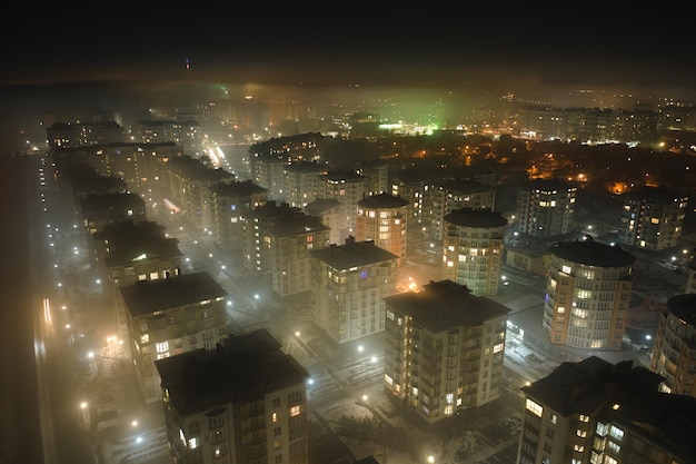 Aerial view of high rise apartment buildings and bright illuminated streets in city residential area at night Dark urban landscape