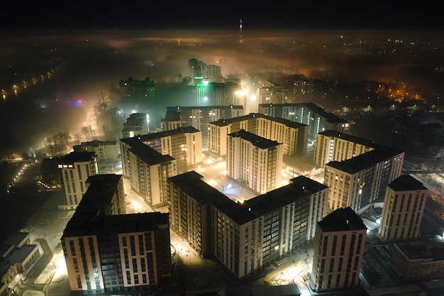 Aerial view of high rise apartment buildings and bright illuminated streets in IvanoFrankivsk city Ukraine residential area at night Dark urban landscape