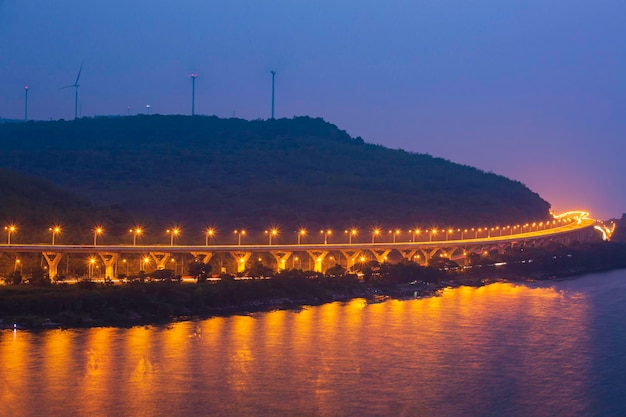 Aerial view of highway splitting around forest hill on a river evening long exposure