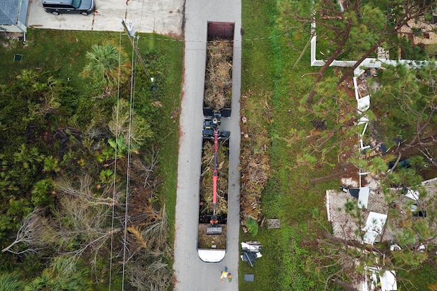 Aerial view of Hurricane Ian special aftermath recovery dump truck picking up vegetation debris from Florida suburban streets Dealing with consequences of natural disaster