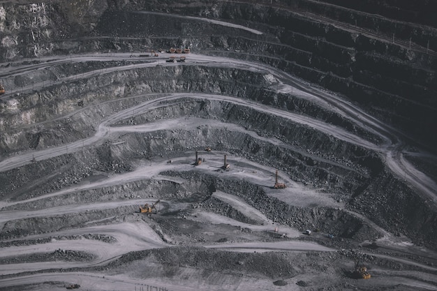 Aerial view industrial of opencast mining quarry with lots of machinery at work - view from above. Extraction of lime, chalk, calx, caol