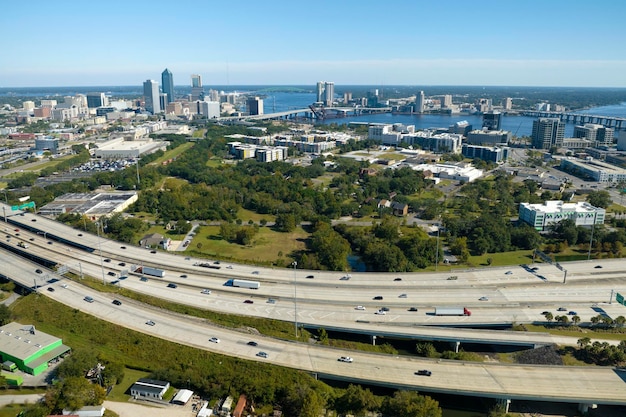 Aerial view of Jacksonville city with high office buildings and american freeway intersection with fast driving cars and trucks View from above of USA transportation infrastructure