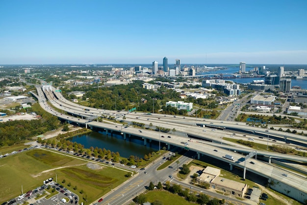 Photo aerial view of jacksonville city with high office buildings and american freeway intersection with fast moving cars and trucks usa transportation infrastructure concept