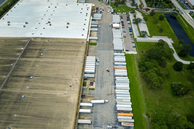 Aerial view of large commercial loading bay with many delivery trucks unloading and uploading retail goods for nationwide distribution Global economy concept