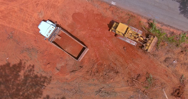 Aerial view of large construction site with several crawler excavator machines in moving earth it onto the dump truck