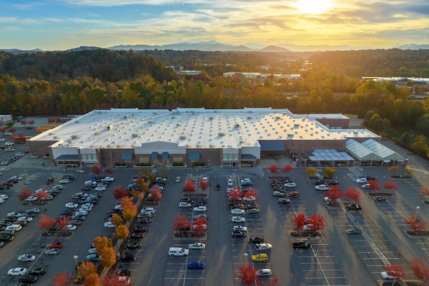 Aerial view of large parking lot in front of rgocery store with many parked colorful cars Carpark at supercenter shopping mall with lines and markings for vehicle places and directions