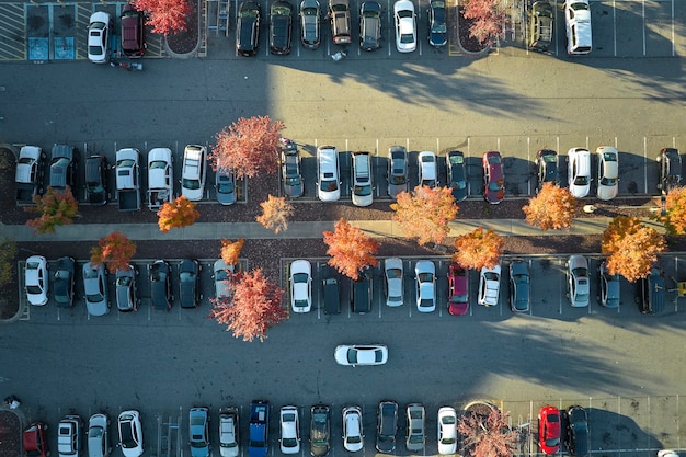 Aerial view of large parking lot with many parked colorful cars Carpark at supercenter shopping mall with lines and markings for vehicle places and directions