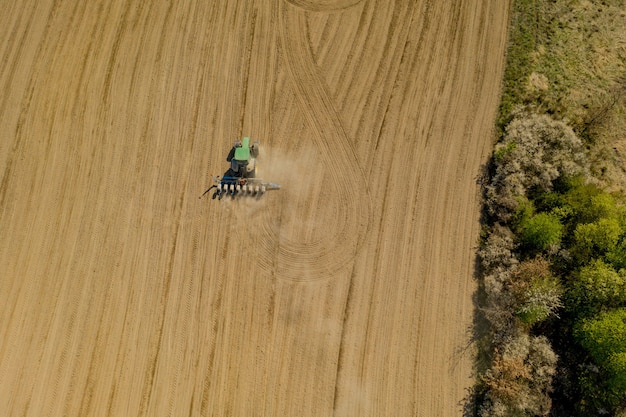 Aerial view large tractor cultivating a dry field.