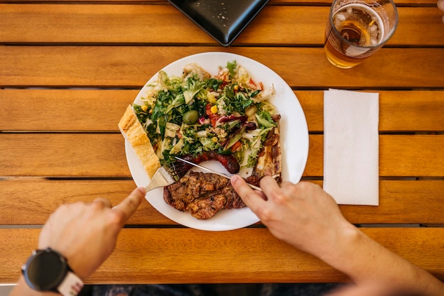 Aerial view of a man slicing a spicy sausage while eating lunch