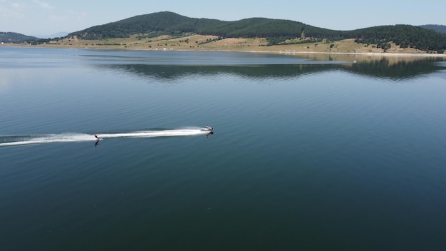 Aerial view of man waker skiing behind a boat on lake at sunset