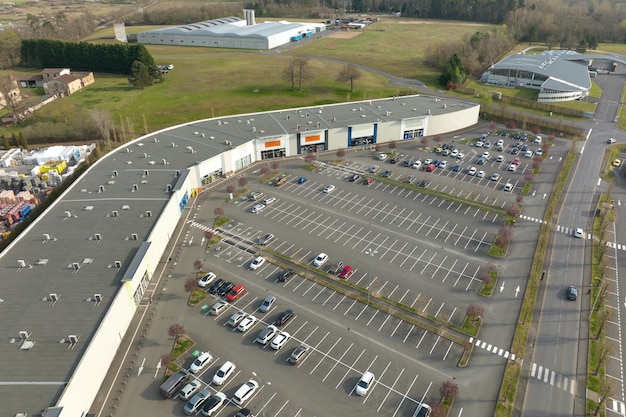 Aerial view of many colorful cars parked on parking lot with lines and markings for parking places and directions