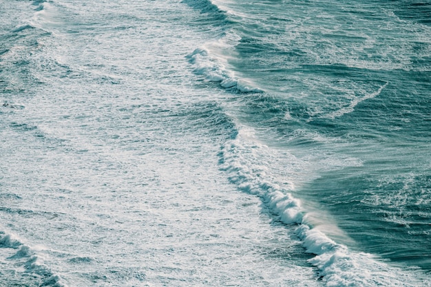 Aerial view of a massive wave crashing in the middle of the ocean