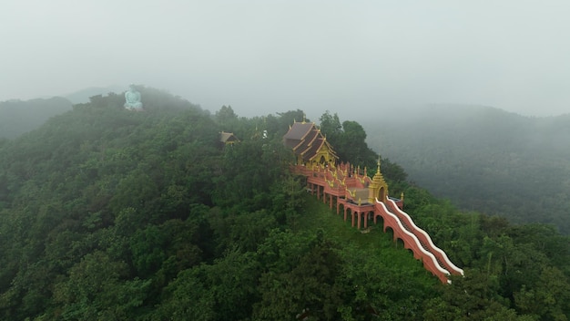 Aerial view at morning mist Wat Phra That Doi Phra Chan and Daibutsu Buddha on the greenery mountain