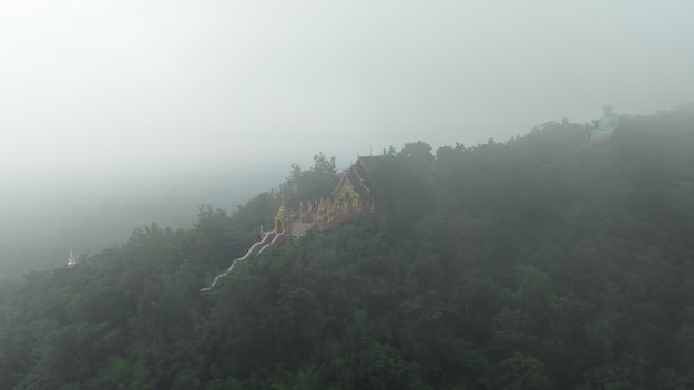 Aerial view at morning mist Wat Phra That Doi Phra Chan and Daibutsu Buddha on the greenery mountain