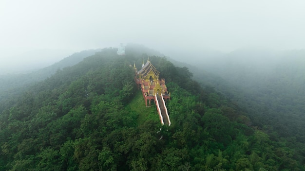 Aerial view at morning mist Wat Phra That Doi Phra Chan and Daibutsu Buddha on the greenery mountain