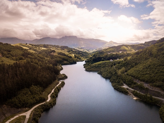 Aerial view of a mountainous river with a road on the edge. Mountain landscape with river