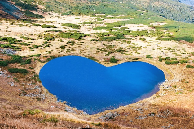 Aerial view of mountains lake with blue water in a shape of heart